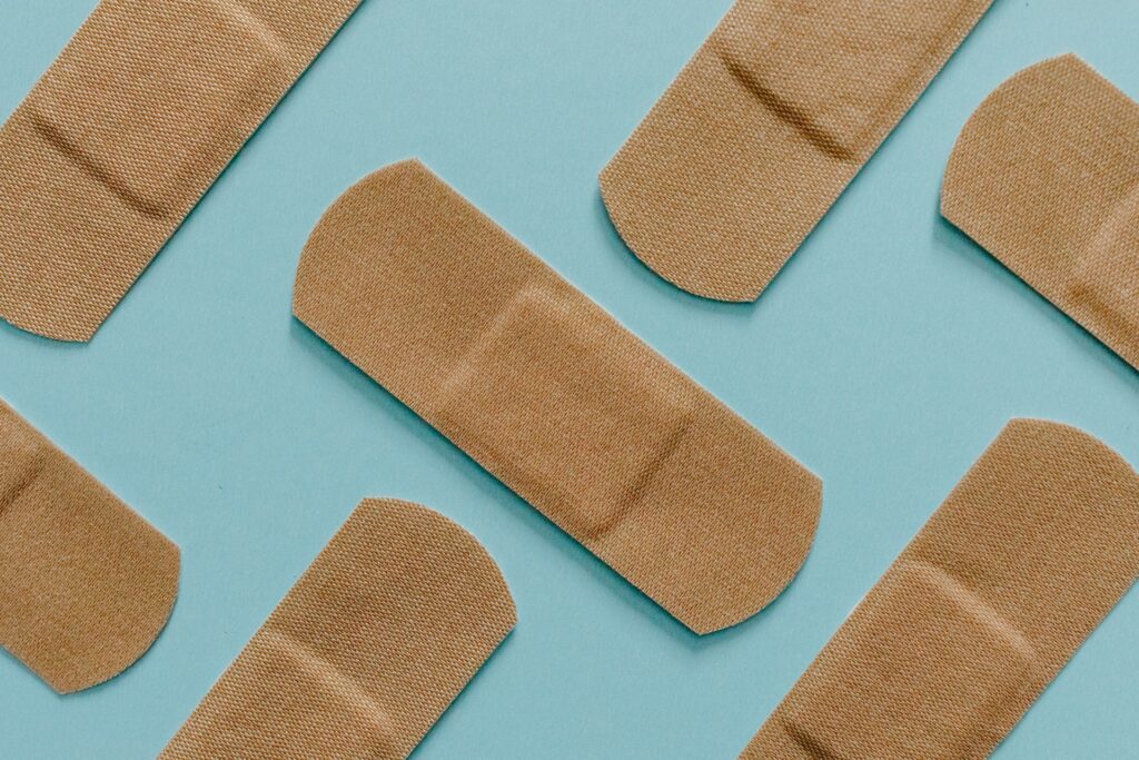 A photo of beige fabric band-aids or plasters placed in a diagonal pattern, where each item alternates between vertical and horizontal orientations on sky blue background